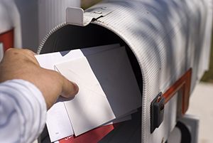 Mano de una persona recogiendo el correo de un buzón.