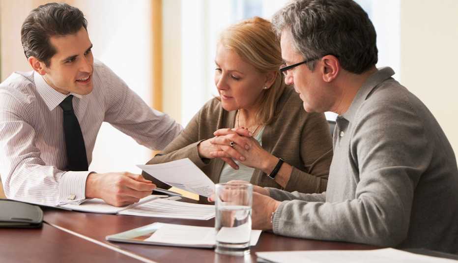 Un consejero mostrando unos papeles a una pareja mayor