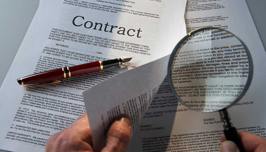 Manos con una lupa viendo un contrato - Errores frecuentes al comprar un negocio