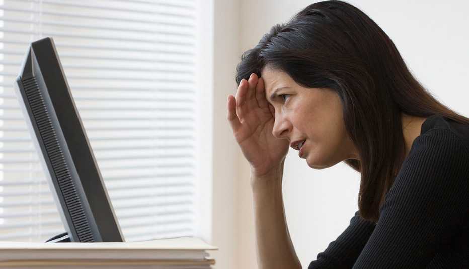 Mujer frente a una computadora con la mano en la frente - Errores frecuentes al comprar un negocio 