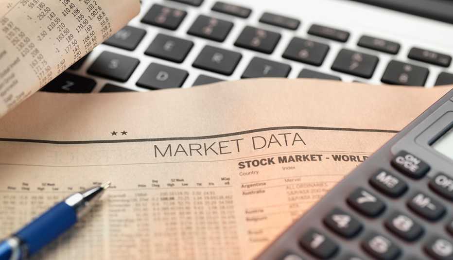 Hoja del mercado de valores sobre una computadora y una calculadora