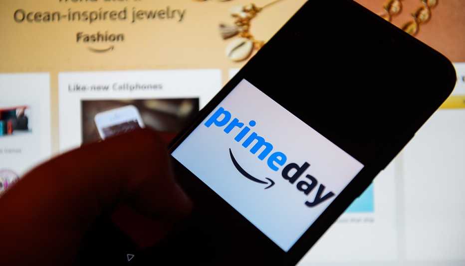 Persona sosteniendo un teléfono móvil y en la pantalla tiene el logo de Prime Day
