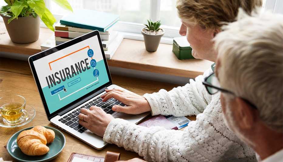 Pareja buscando seguros en línea a través de una computadora portátil.