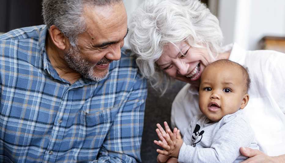 Abuelos sentados en un sofá sosteniendo a su nieto