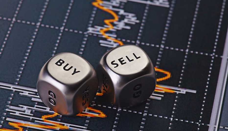 Dados metálicos con las palabras comprar y vender sobre una gráfica estadística del mercado de valores.