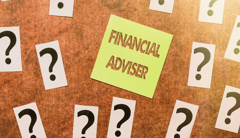 Tablero de notas con interrogantes y un papel de notas que dice asesor financiero en inglés