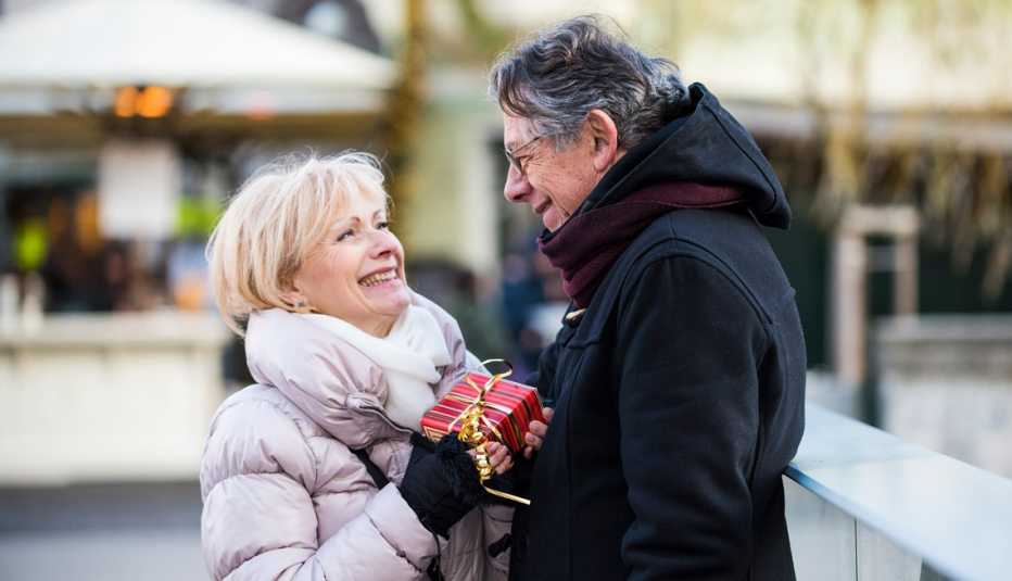 Pareja con ropa de invierno intercambia regalos