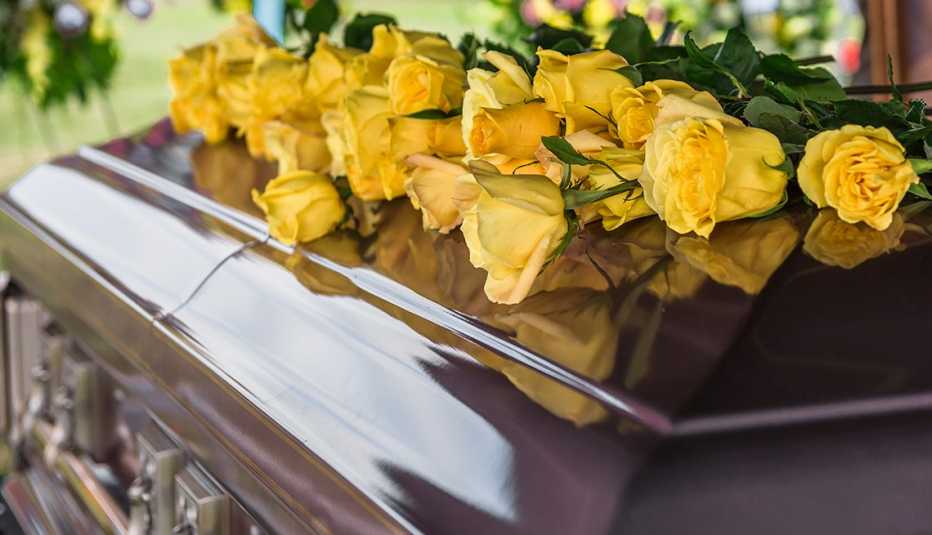 Un ataúd con flores amarillas encima.