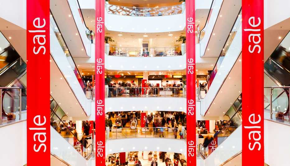 Panorámica del interior de un centro comercial con pendones rojos que dicen rebaja