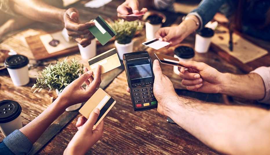 Manos de personas con tarjetas de crédito sobre una mesa para pagar la cuenta de un restaurante
