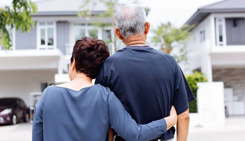 Una pareja se abraza frente a su hogar
