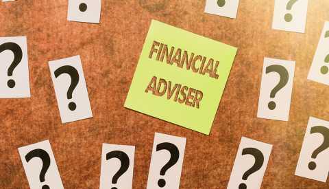 Tablero de notas con interrogantes y un papel de notas que dice asesor financiero en inglés
