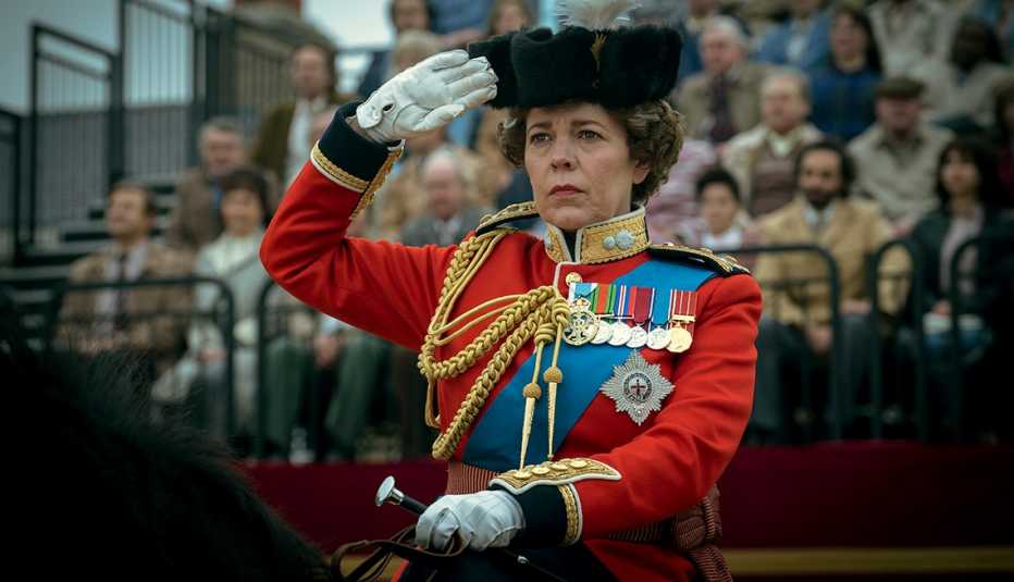Olivia Colman, como la reina Isabel II, saluda mientras monta a caballo en una escena de The Crown.