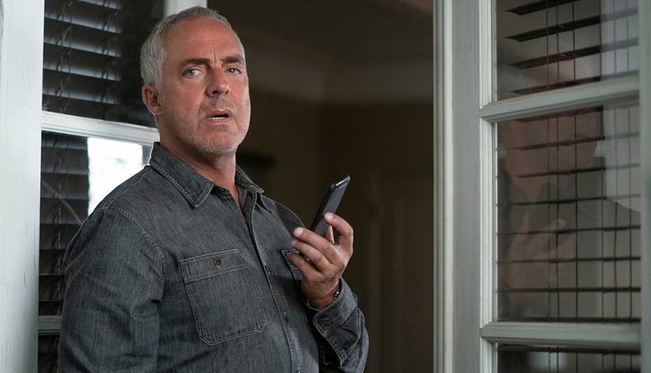 Titus Welliver como Harry Bosch sostiene un teléfono celular en una escena de Bosch Legacy.