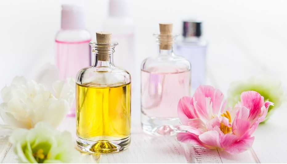 Frascos de vidrio con aceites faciales con unas flores a los lados.