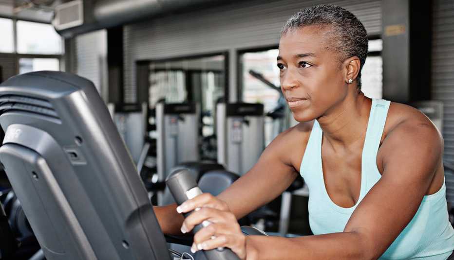 Una mujer con una bicicleta estática en el gimnasio.