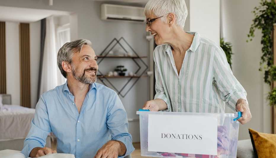 Una mujer y un hombre preparando una caja de donación.