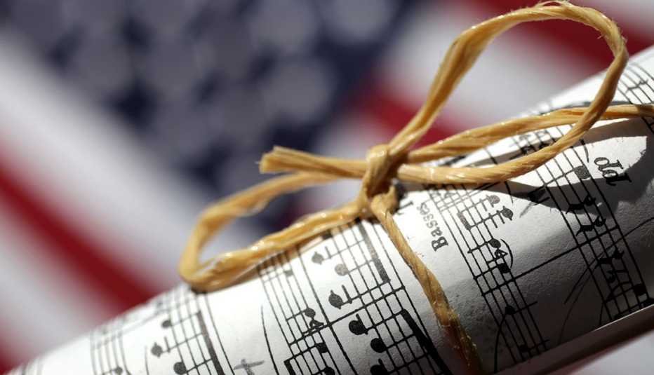 Partitura amarrada con un lazo y al fondo una bandera de Estados Unidos