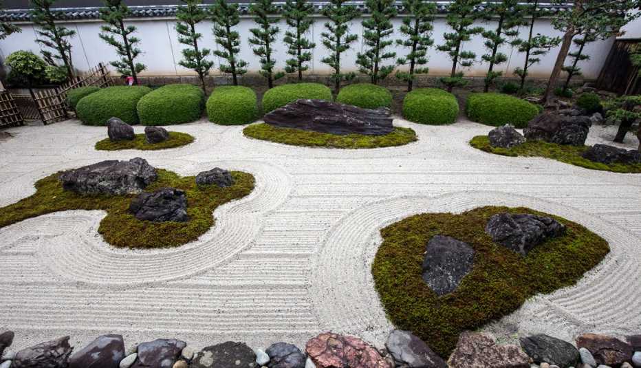 Jardín zen con rocas, musgo y árboles.