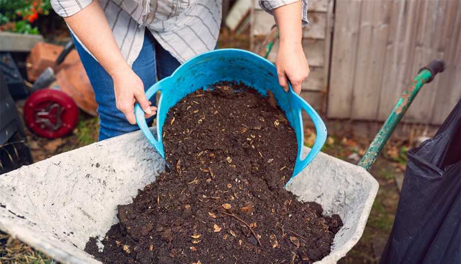 Una mujer echa compost en una carretilla