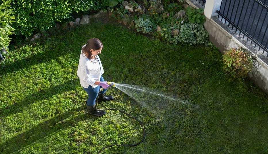 Mujer regando el césped con una manguera