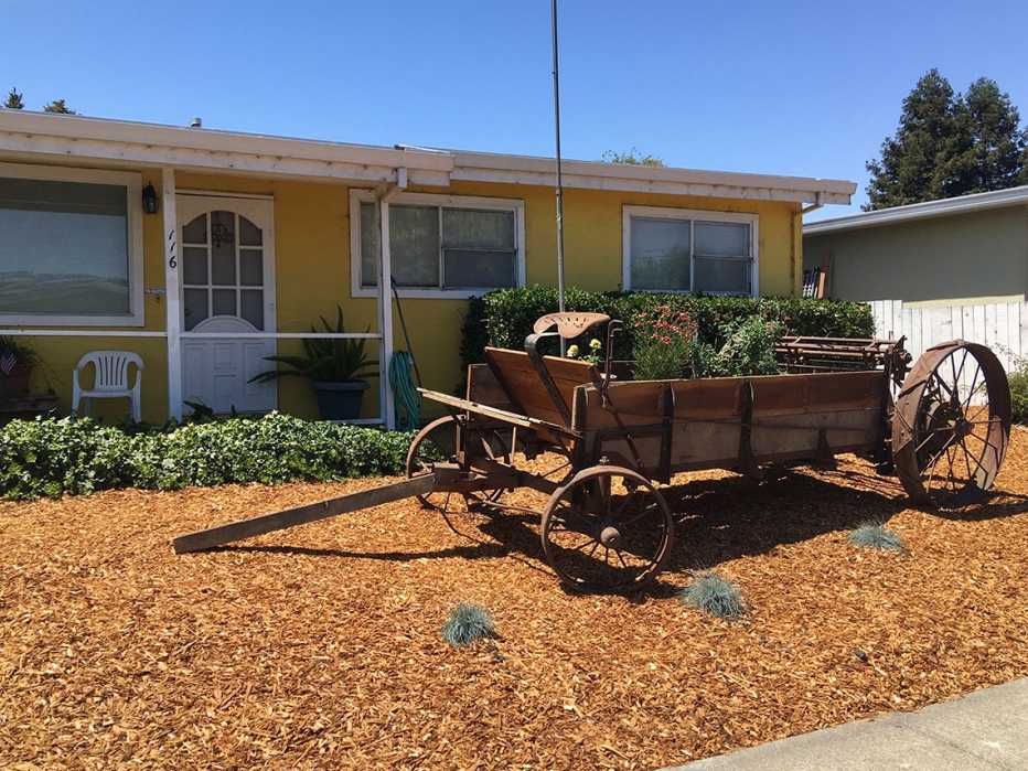 Carreta llena de plantas en frente de una casa
