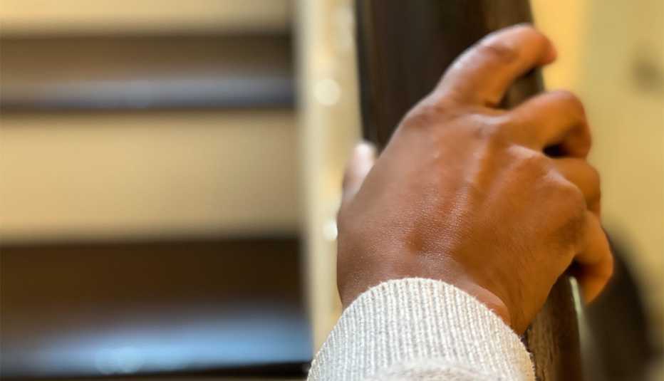 Mujer se sostiene de la baranda mientras sube escaleras