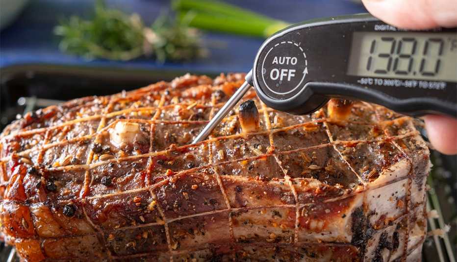 Persona mide la temperatura de la carne con un termómetro digital