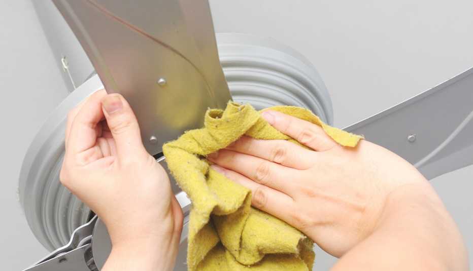 Persona limpia un ventilador de techo 