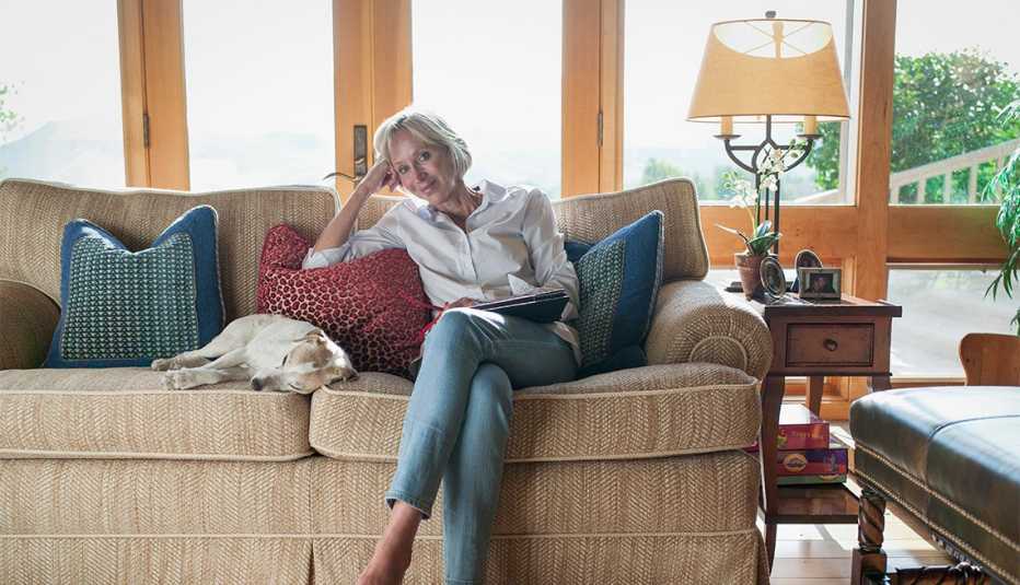 Mujer está sentada en un sofá con su perro