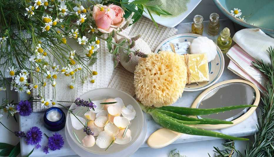 Mesa con flores y plantas, aloe vera, aceites aromáticos, esponja natural y jabones