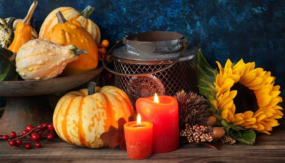 Recipiente de metal rodeado de calabazas, velas y flores