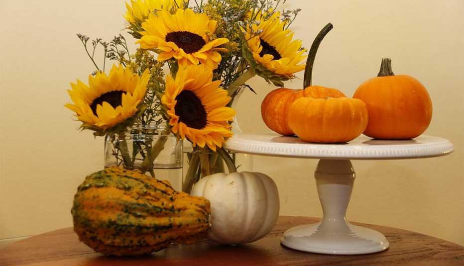 Calabazas puestas sobre una base alta de porcelana rodeada de flores 