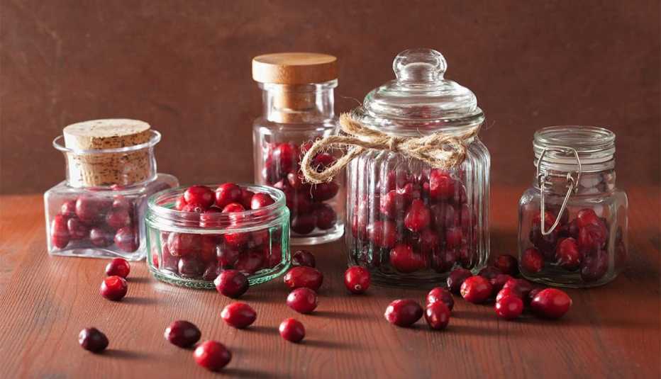 Cinco botellas de vidrio con arándanos rojos