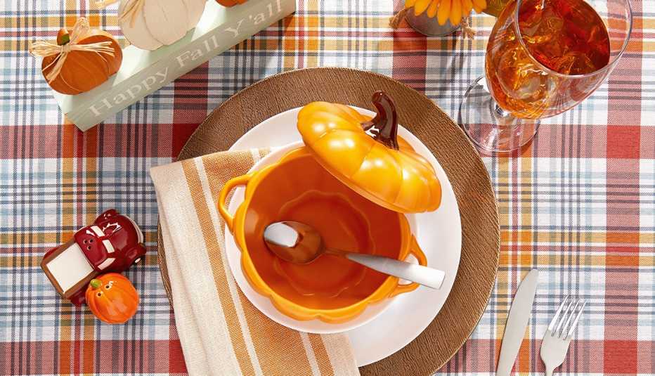 Mesa con con un mantel a cuadros y algunos accesorios de otoño 
