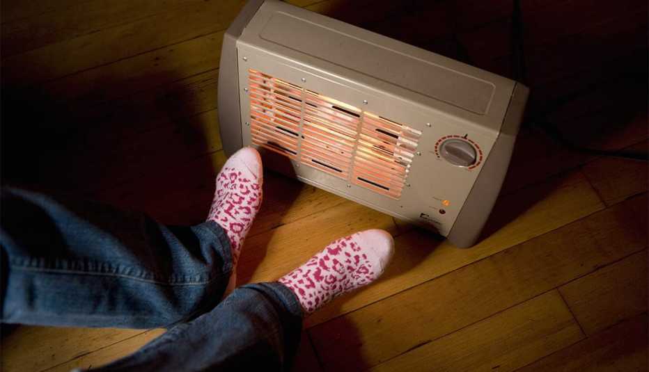 Dos pies junto a un calentador eléctrico portátil