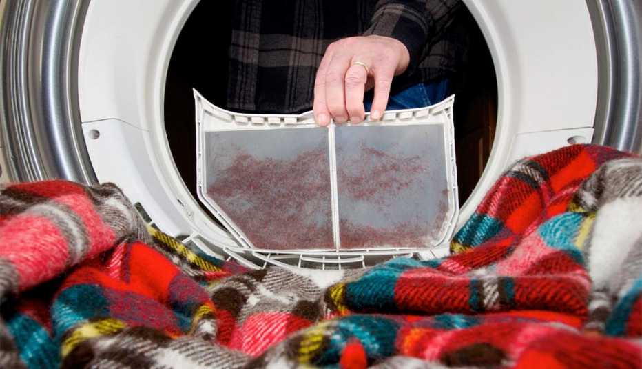 Una mano retirando la rejilla de ventilación de una secadora