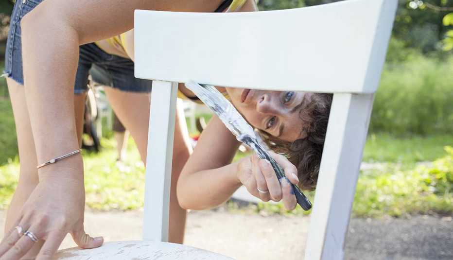 Mujer pintando de color blanco una silla 