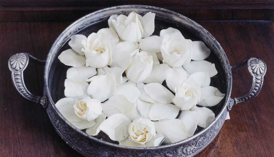 Recipiente metálico y tallado con gardenias dentro de él