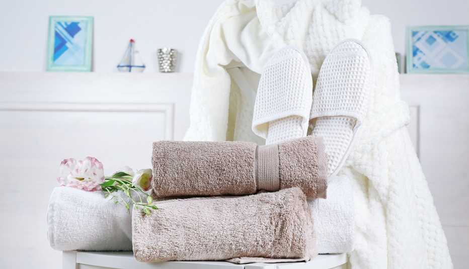 Toallas, albornoz y zapatillas sobre una silla blanca