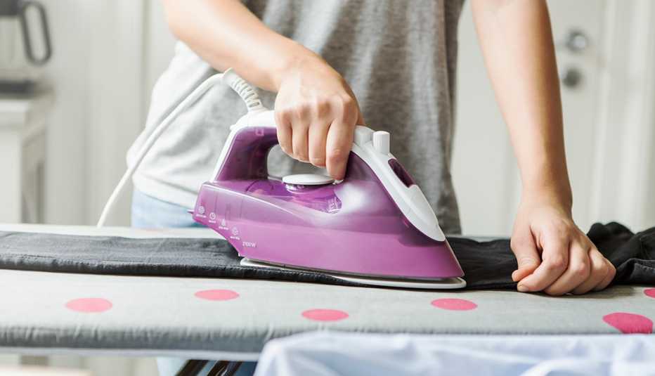 Una persona planchando un pantalón sobre una tabla de plancha