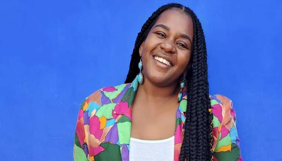 La ganadora de Benefits Badass, de AARP, Jihane Jeanty, de pie frente a un fondo azul.