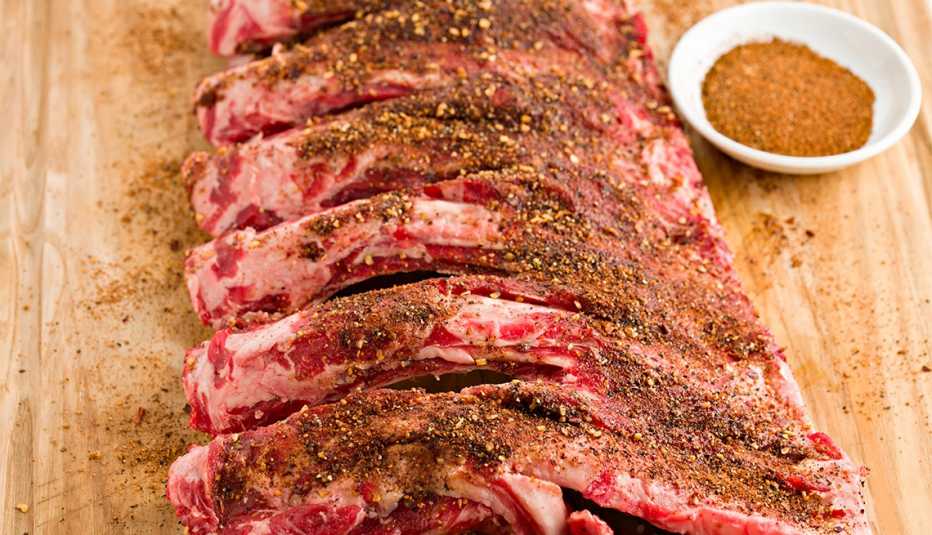 Costillas de res crudas junto a una taza de aliño