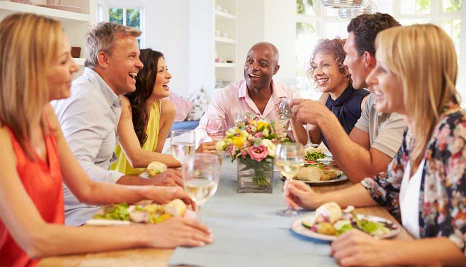 Grupo de amigos sentados alrededor de la mesa mientras cenan