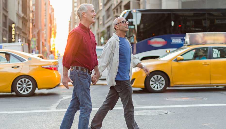 Pareja masculina tomada de la mano cuando cruza una calle