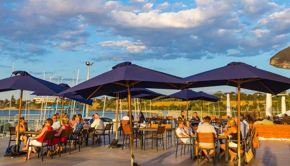 Zona al aire libre frente al mar con gente en varias mesas