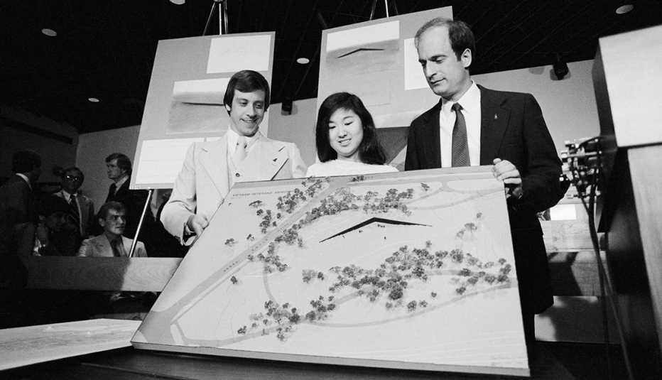 Foto en blanco  y negro de donde Maya Lin, Jan Scruggs y Bob Doubek, muestran una maqueta del monumento a los veteranos de Vietnam en 1981.