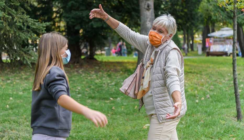 Abuela saluda a su nieta mientras llevan puestas máscaras quirúrgicas
