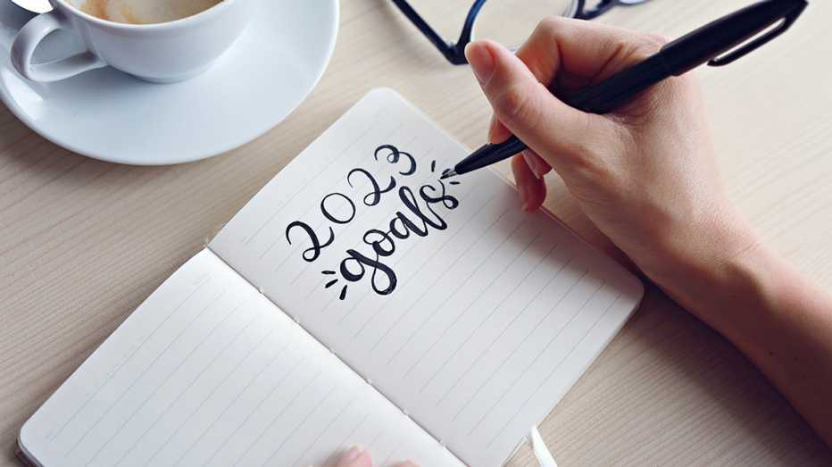 Mano de una persona que escribe en una libreta metas del 2023