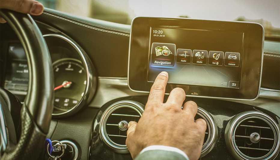 Conductor toca la pantalla táctil de un auto